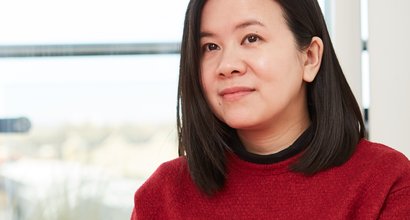 Jacqueline, diagnosed with diffuse large b-cell lymphoma, looks beyond camera in a red jumper.