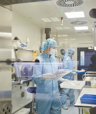 Three researches in full body personal protective equipment conducting tests in a research facility.
