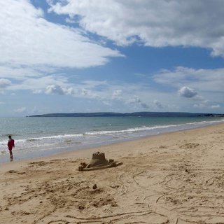 A beach scene with a sandcastle and the sea showing in the background.